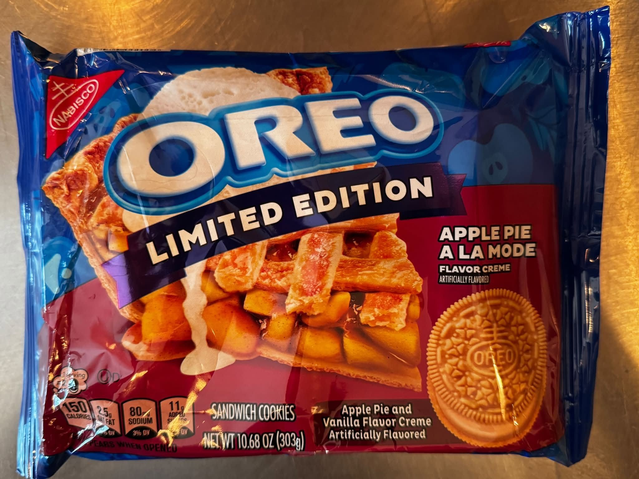 A blue Oreo Limited Edition package labeled 'Apple Pie a la Mode Flavor Creme,' with a slice of lattice-topped apple pie drizzled with cream and a golden Oreo sandwich cookie.