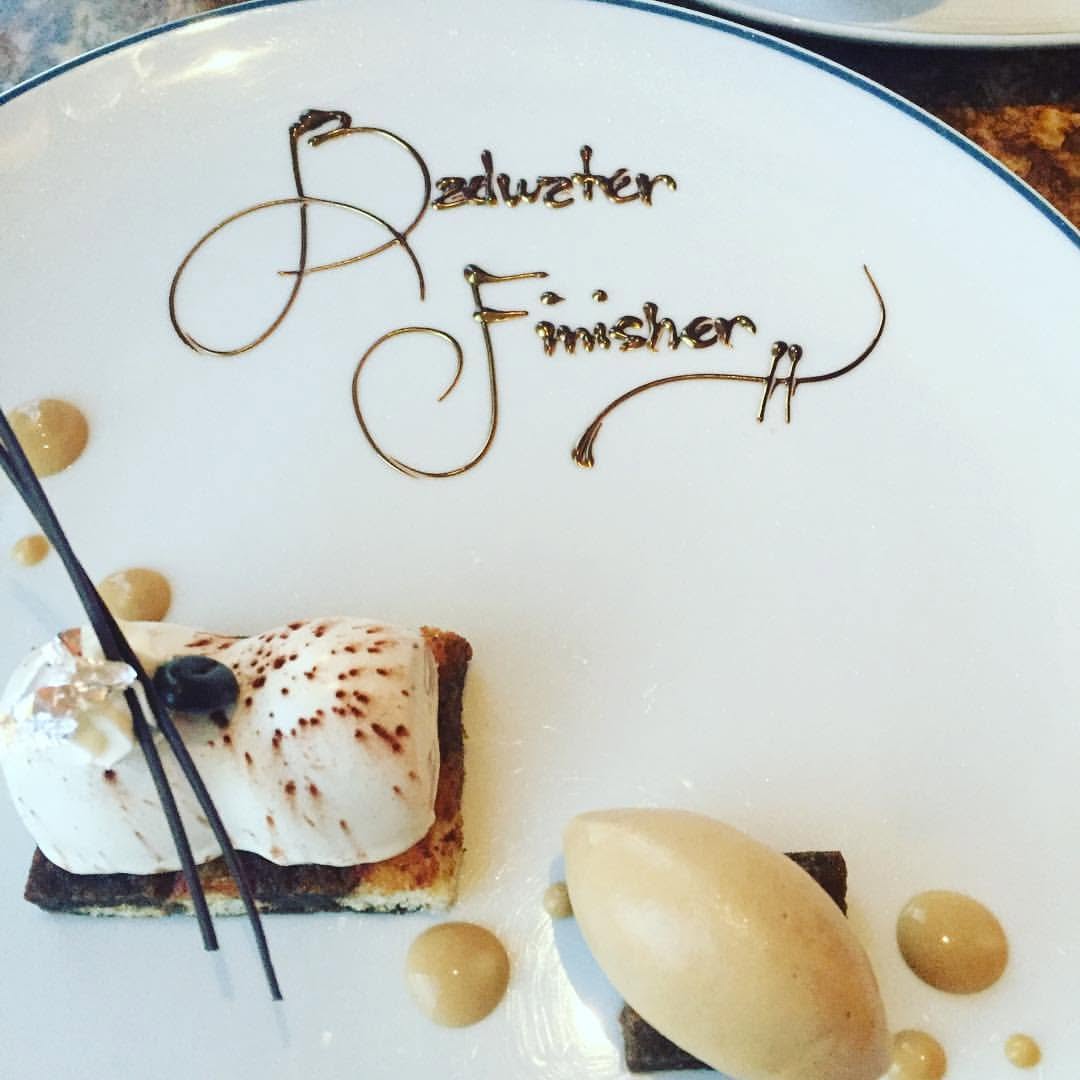 A plated restaurant dessert with 'Badwater Finisher' written in chocolate script, a toasted-meringue tart and a quenelle of ice cream alongside.