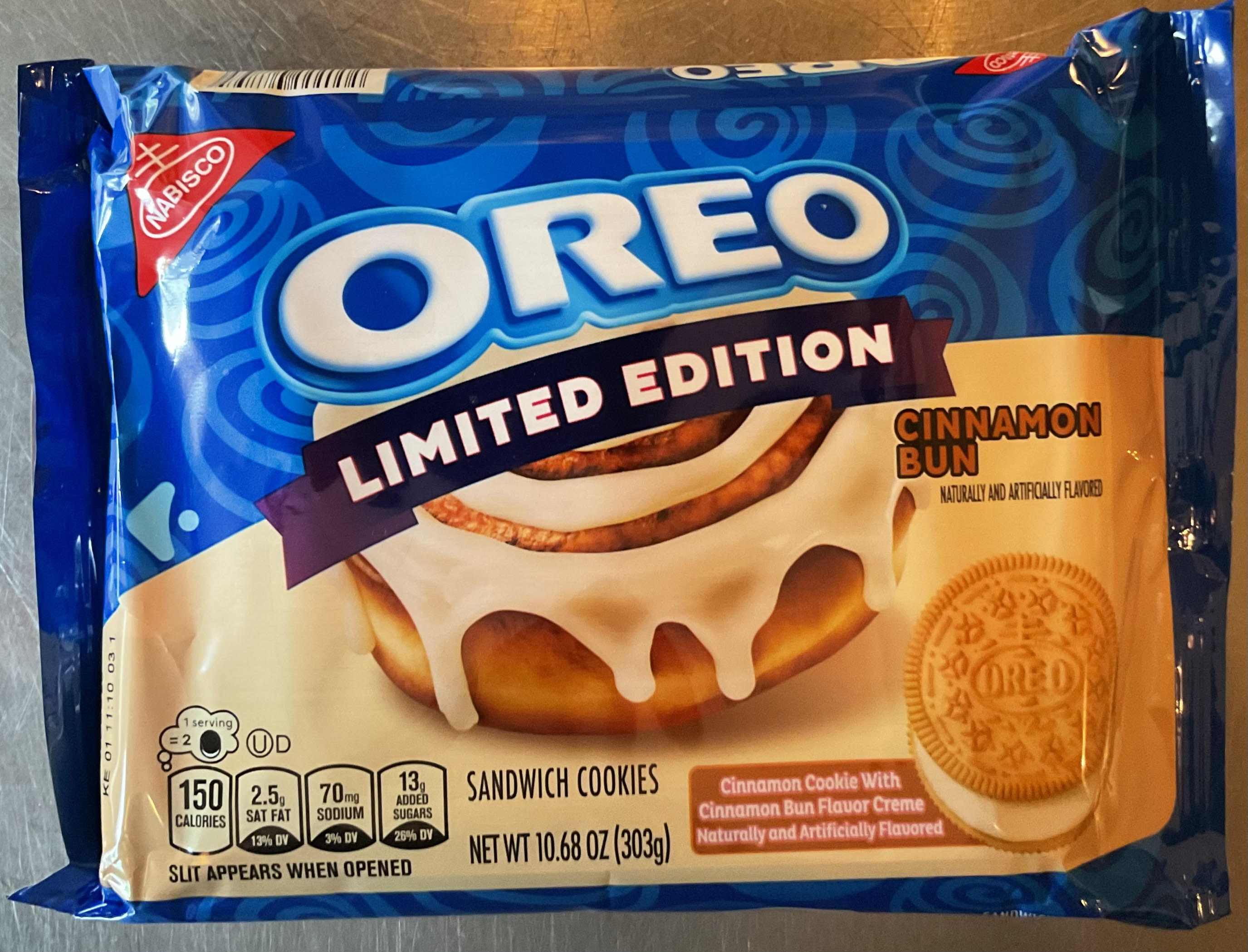 A blue Oreo Limited Edition package with a swirled background, an iced cinnamon bun graphic, and 'Cinnamon Bun' flavor lettering, with a single golden Oreo cookie pictured at the bottom right.