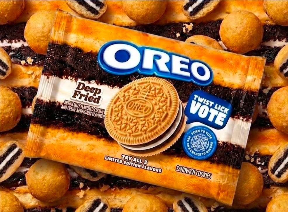An orange Oreo Limited Edition package labeled 'Deep Fried' with a 'Twist Lick Vote' badge and a golden sandwich cookie, sitting on a pile of fried Oreo bites.