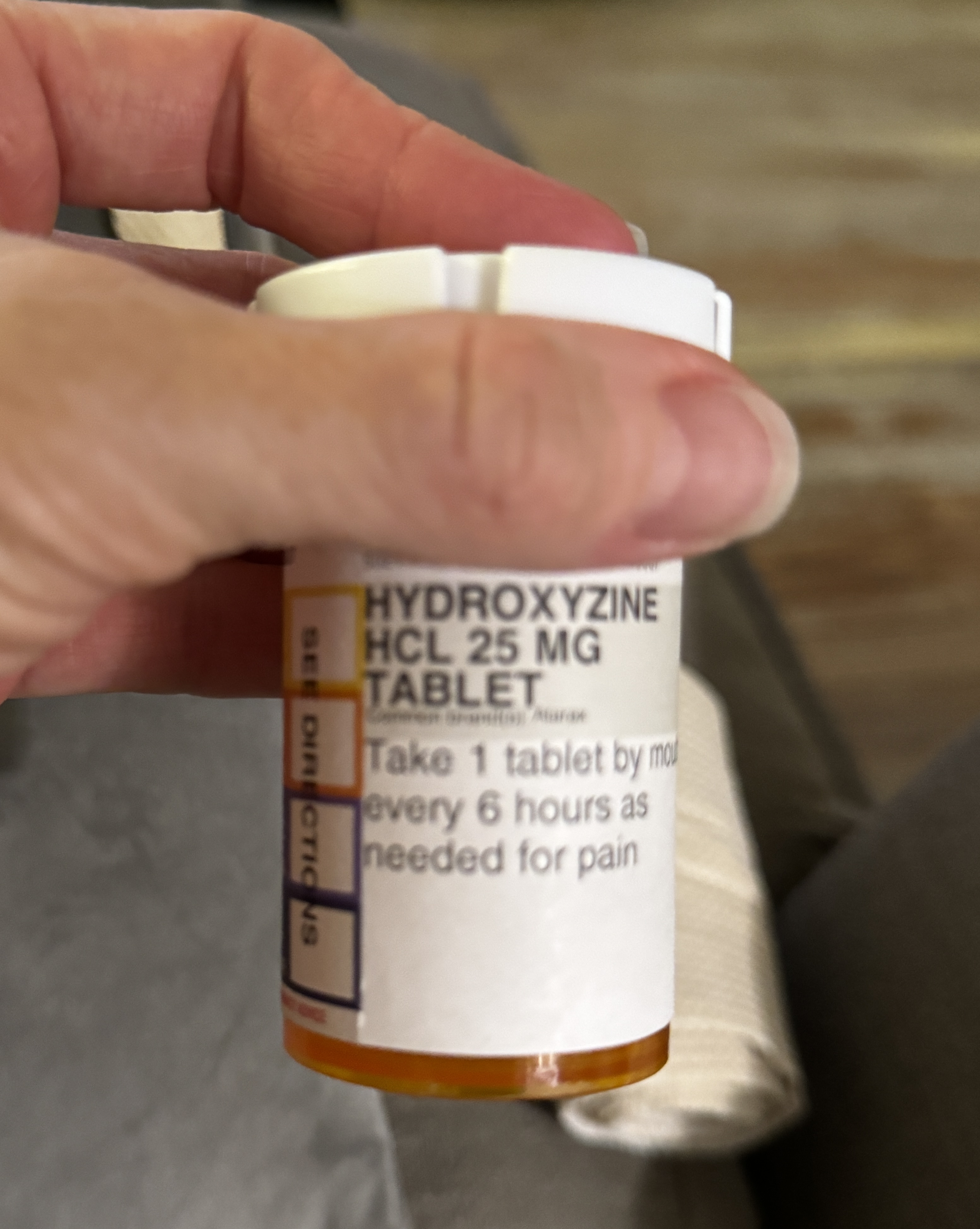 My hand holding the prescription bottle: hydroxyzine HCl 25 mg tablets, one by mouth every six hours as needed.