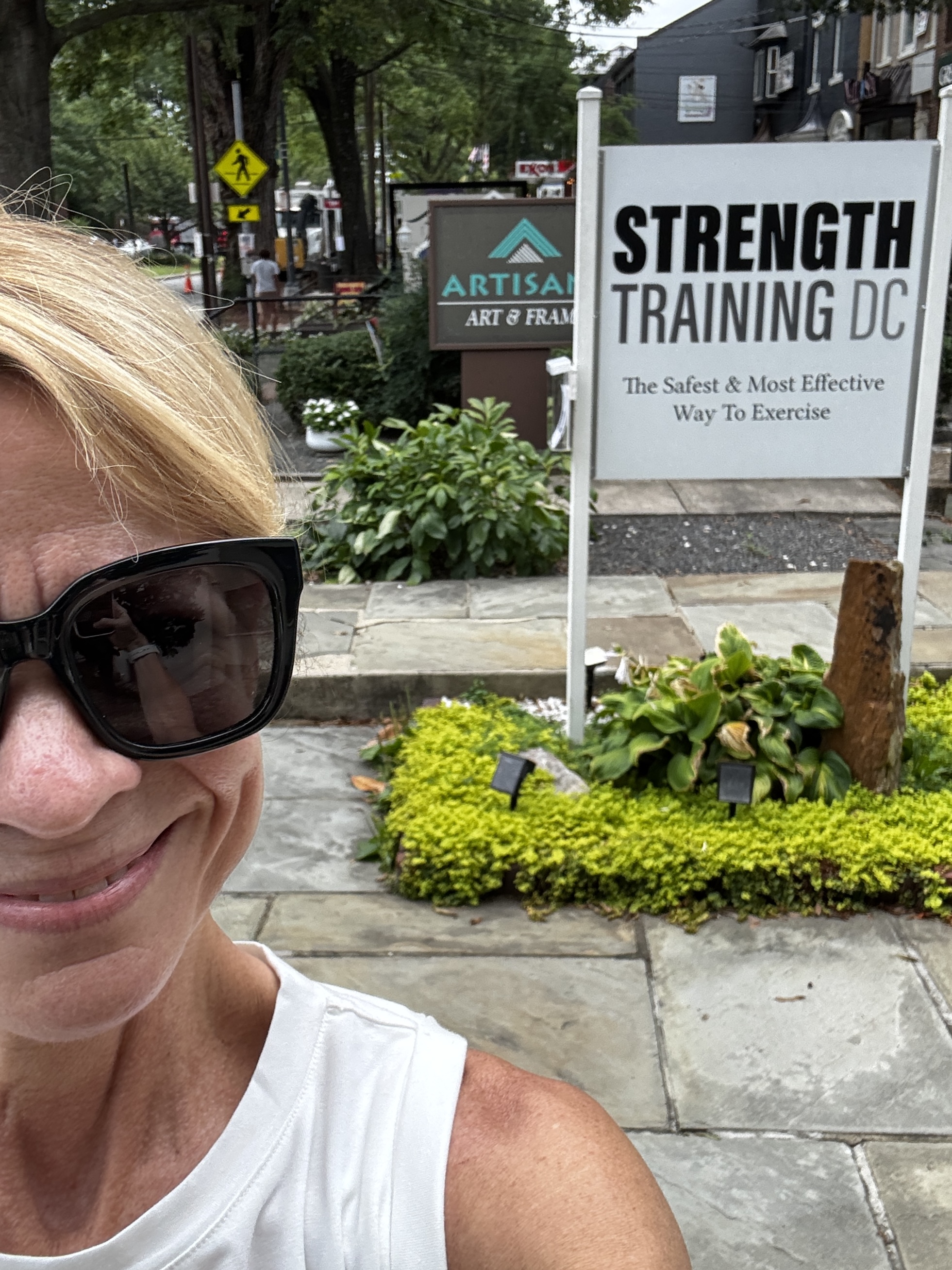 A sweaty post-workout selfie in front of the Strength Training DC sign, which promises 'The Safest & Most Effective Way To Exercise.' I can confirm: safe, effective, and 100 yards from my couch.
